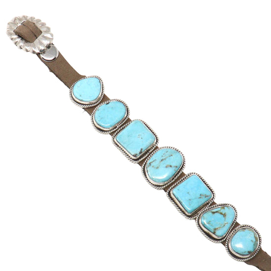 Bracelet with turquoise stones and brown leather strap on a white background