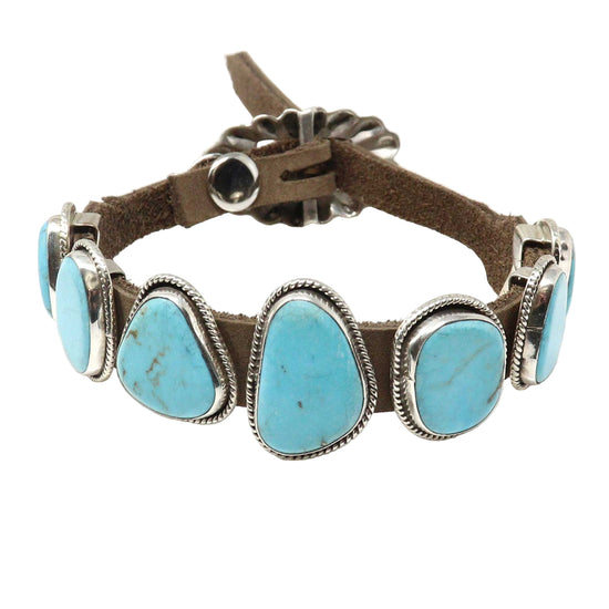 Bracelet with turquoise stones and brown leather strap on a white background