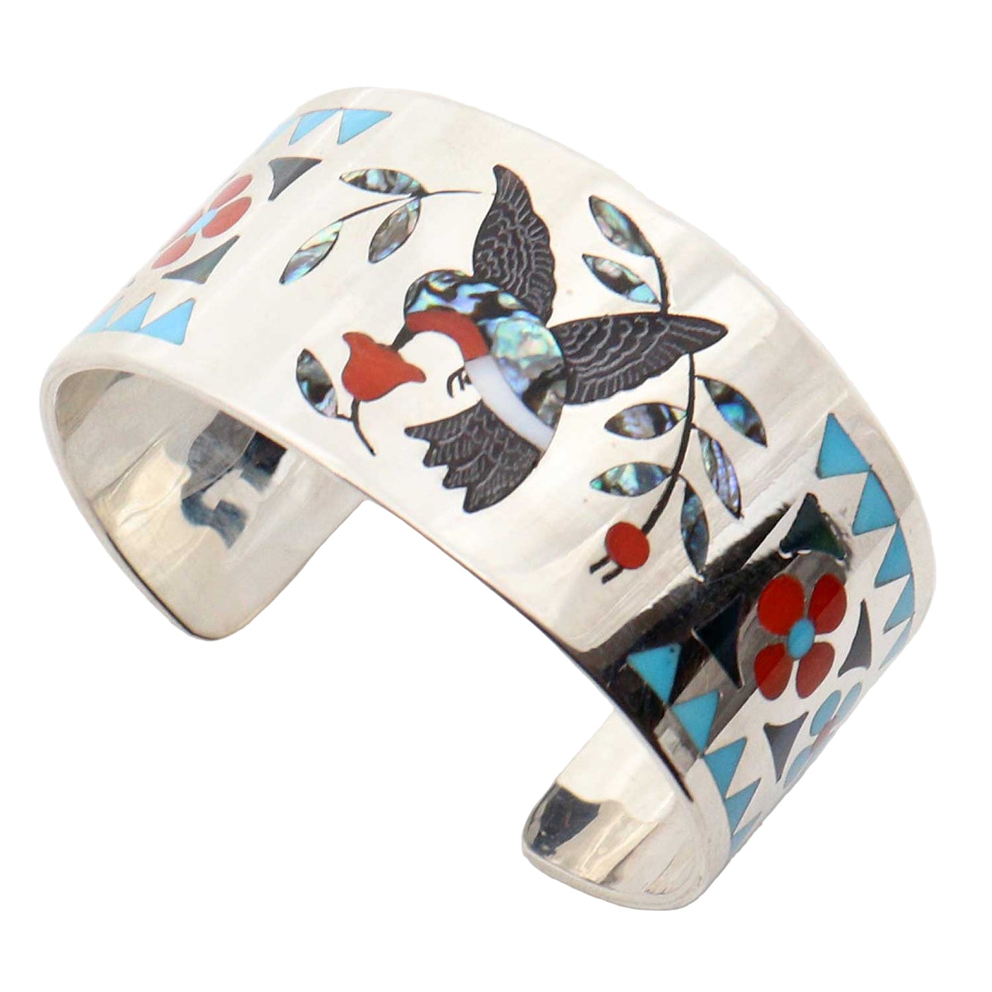 Silver cuff bracelet with inlaid design of a hummingbird and geometric patterns on a white background