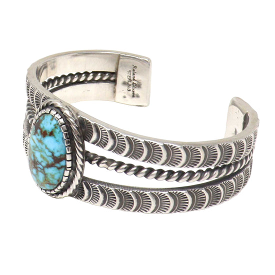 Silver cuff bracelet with turquoise stone on a white background