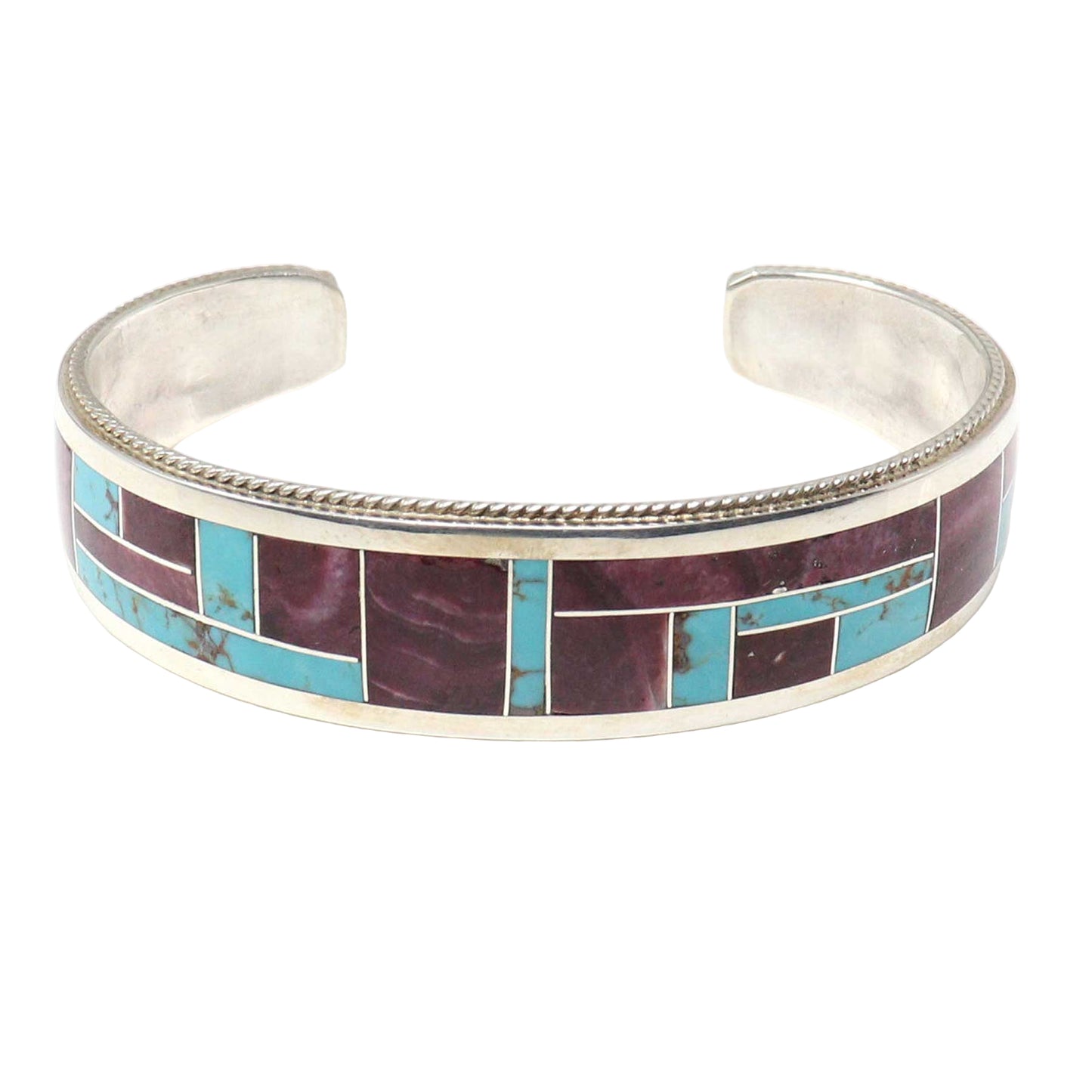 Silver bracelet with inlaid purple and turquoise stones on a white background