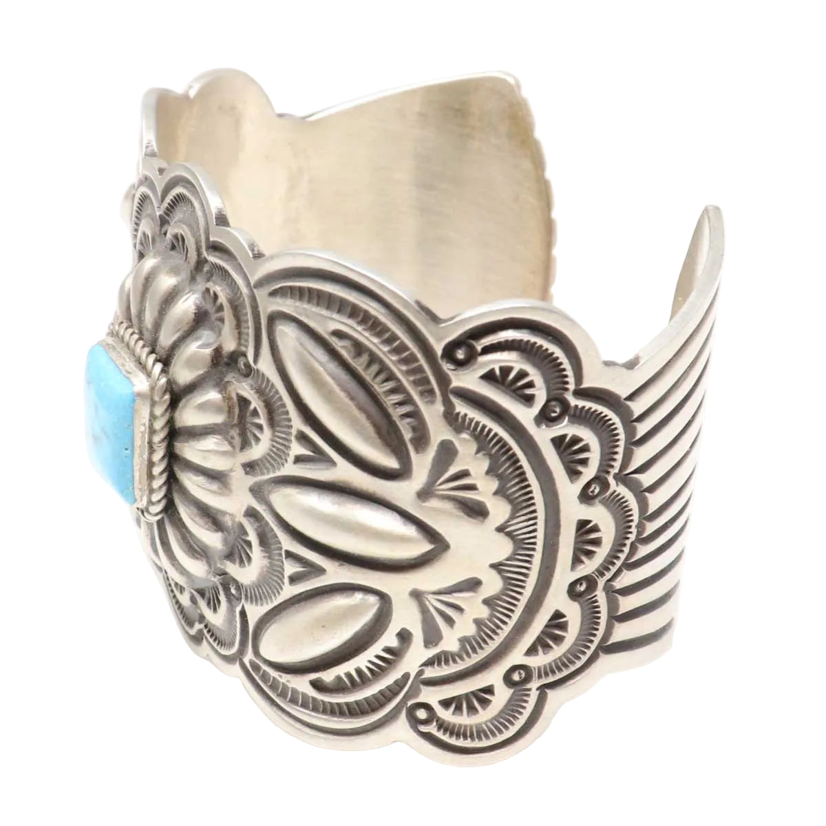 Silver cuff bracelet with intricate designs and a turquoise stone on a white background