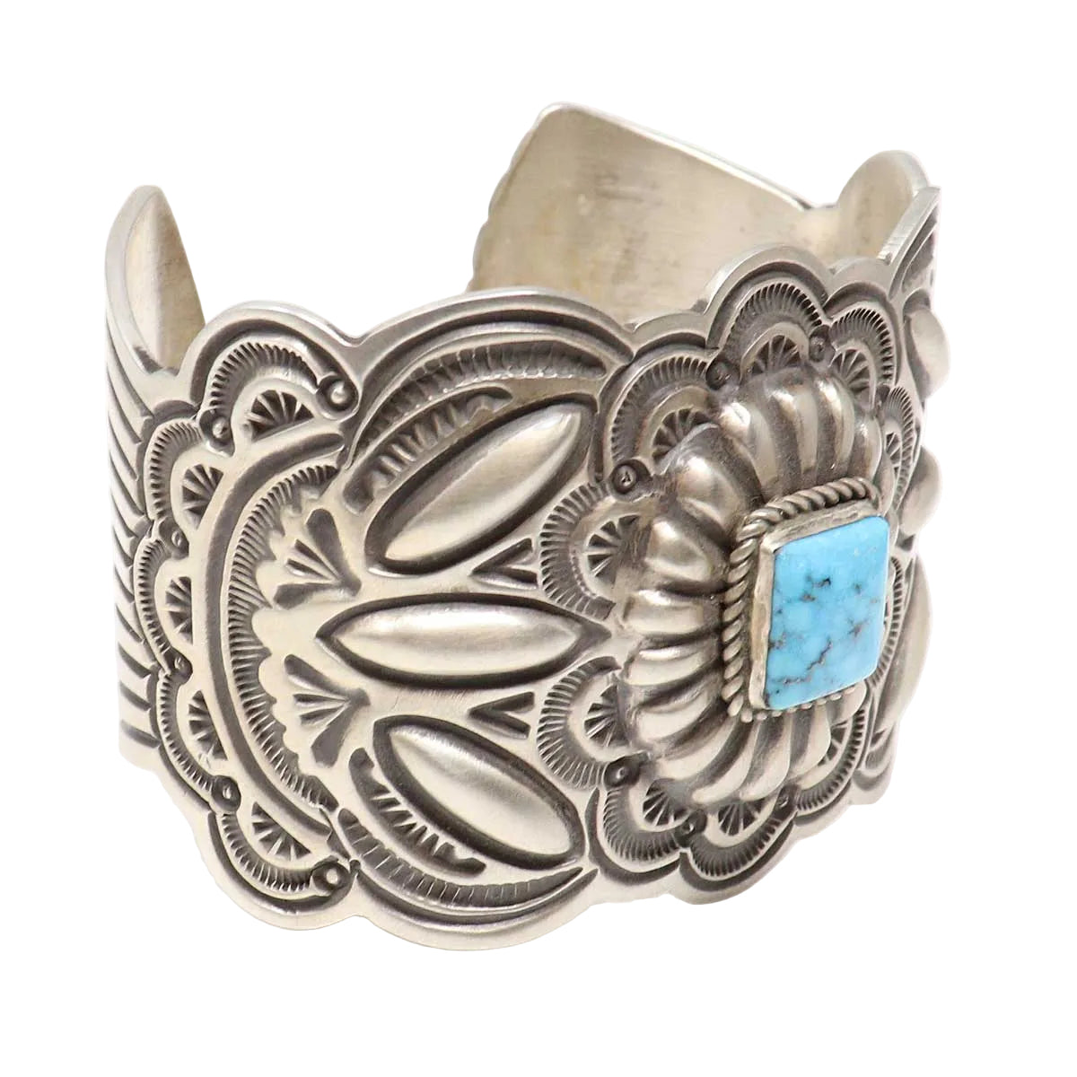Silver cuff bracelet with intricate designs and a turquoise stone on a white background