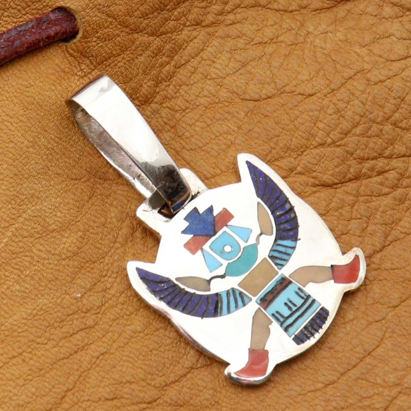Silver pendant with colorful design on a brown leather background