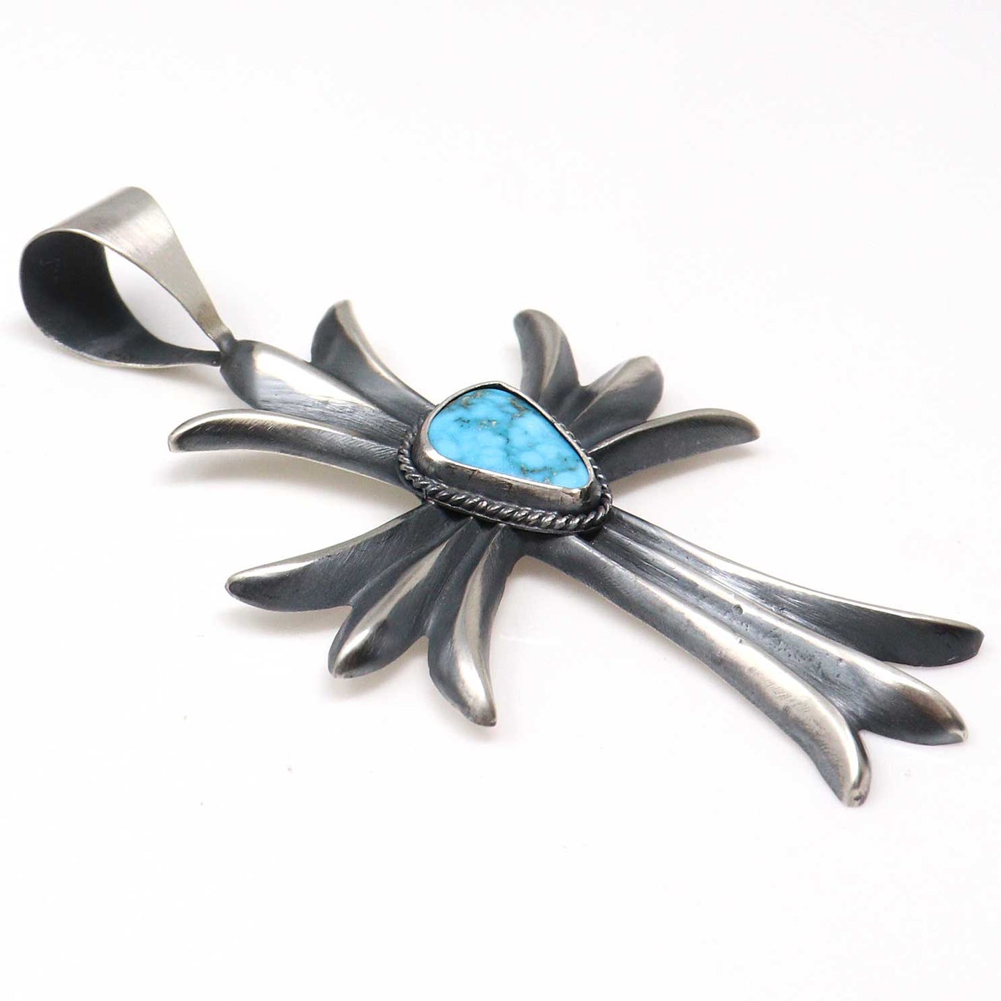Silver cross-shaped pendant with a blue stone on a white background