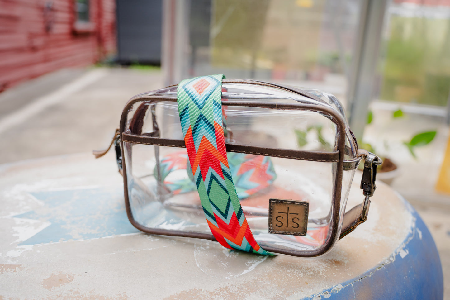 Clear bag with a colorful strap on a textured surface