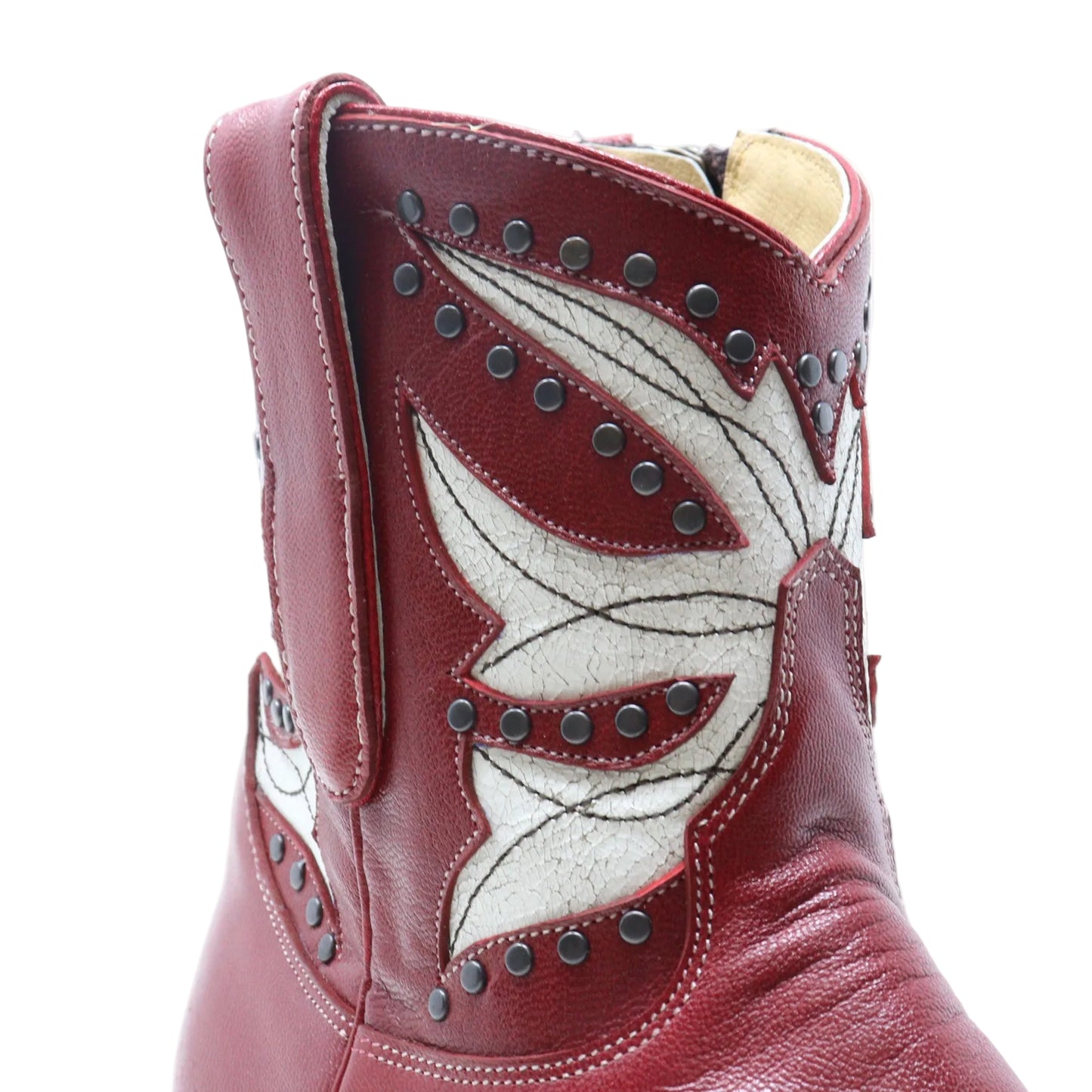 A close-up of a western boot in burgundy leather with a large white feather applique and dark metal studs, shown against a plain white background.
